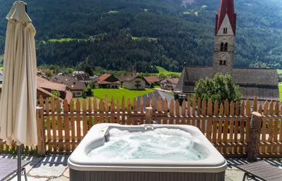 a bath tub sitting on a balcony with a church at Apartments, Guest House & historic Chalet Neuhaus in San Sigismondo
