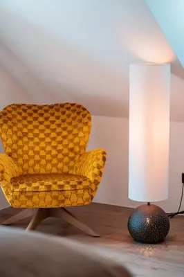 a yellow chair and a lamp on a table at Apartments, Guest House & historic Chalet Neuhaus in San Sigismondo