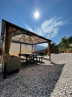 a picnic shelter with a picnic table and the sun at Apartments, Guest House & historic Chalet Neuhaus in San Sigismondo