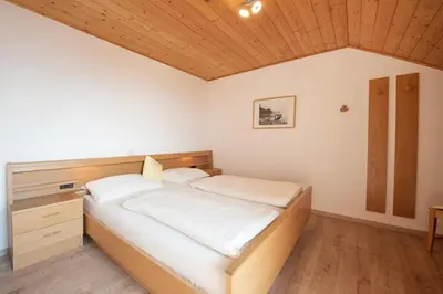 a bedroom with a bed with white sheets and a wooden ceiling at Puitnhof in Caldaro