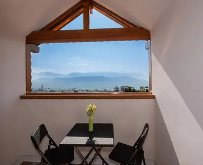 a table and chairs in a room with a large window at Puitnhof in Caldaro