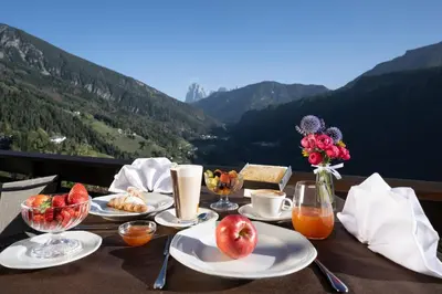 a table with plates of food and a view of mountains at Hotel Überbacher in Laion