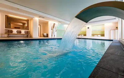 a pool with a water fountain in a hotel at Hotel Überbacher in Laion