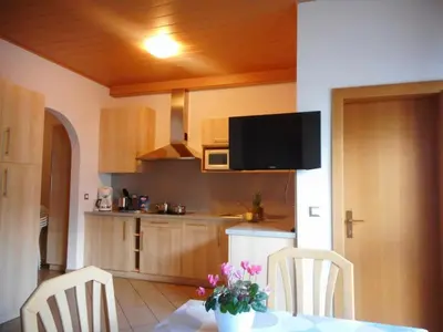 a kitchen with a table and two chairs and a television at Residence Hofer in Valdaora
