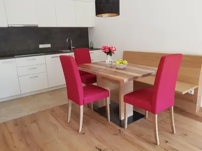 a kitchen with a wooden table and pink chairs at Lahnhof in Lana