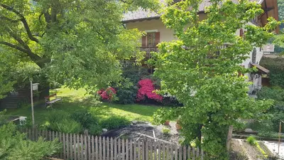 a house with a fence and a yard with flowers at Lahnhof in Lana