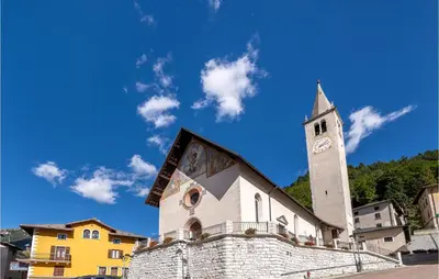 a church with a tower with a clock on it at Beautiful Home In Castello Tesino in Castello Tesino
