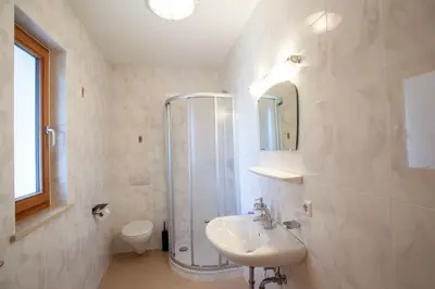 a white bathroom with a shower and a sink at Hof Schupfer - Alpstay in Naturno