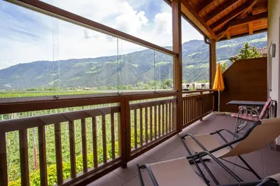 a balcony with chairs and a table and a view of mountains at Hof Schupfer - Alpstay in Naturno