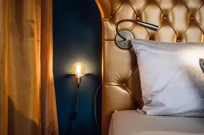 a bed with a headboard with a lamp next to it at Loom in Bolzano