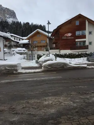 a building with snow on the side of a street at ALBERGO BAR RISTORANTE DOLOMIA in Badia