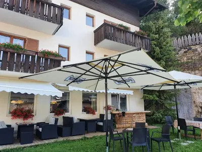 a patio with tables and chairs and an umbrella at ALBERGO BAR RISTORANTE DOLOMIA in Badia
