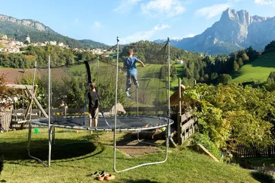 a boy and a girl jumping on a trampoline at Nuierhof in Castelrotto