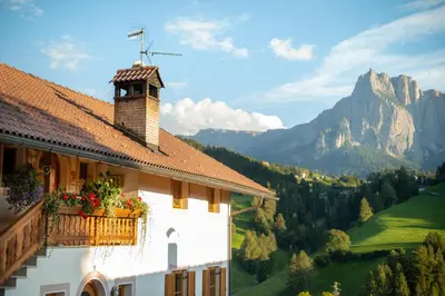 a building with flowers on a balcony with a mountain at Nuierhof in Castelrotto