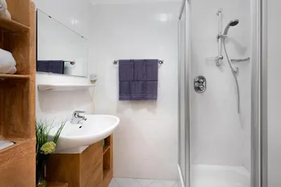 a white bathroom with a sink and a shower at Nuierhof in Castelrotto