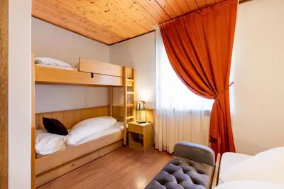a bedroom with two bunk beds and a window at Albergo Dolomiti in Cavalese