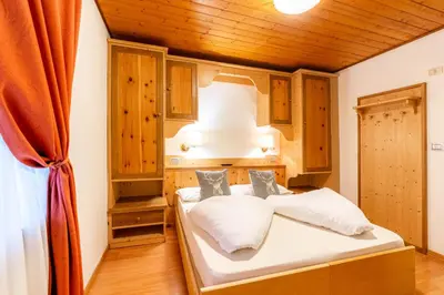 a bedroom with a bed with white sheets and wooden ceilings at Albergo Dolomiti in Cavalese