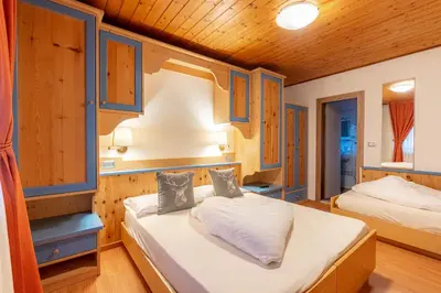 a bedroom with two beds and blue cabinets at Albergo Dolomiti in Cavalese
