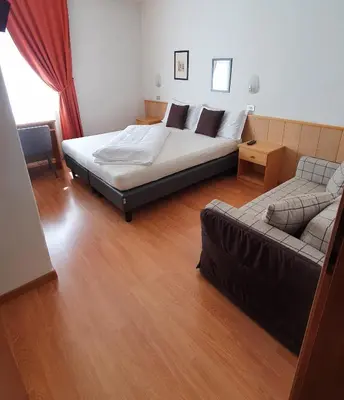 a bedroom with a bed and a couch in it at Albergo Dolomiti in Cavalese