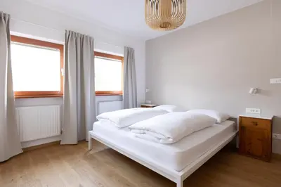a white bed in a white room with windows at Valentinhof - organic farm in Merano