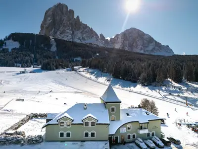 a house in the snow with mountains in the background at Villa Pana in Santa Cristina in Val Gardena