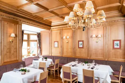 a dining room with two tables and a chandelier at Hotel Restaurant Lilie in Vipiteno