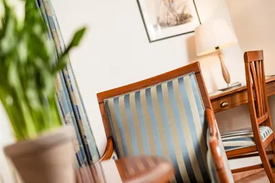 a wooden chair sitting next to a desk with a lamp at Hotel Restaurant Lilie in Vipiteno