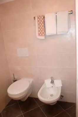 a bathroom with a toilet and a sink and towels at Residence Viktoria in Castelrotto