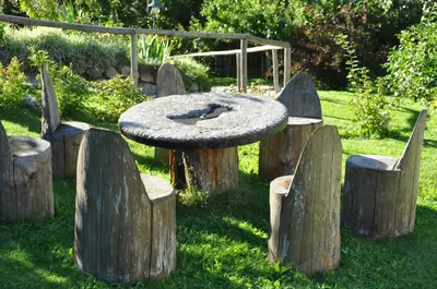 a table with logs around it in the grass at Ortnerhof in Gais