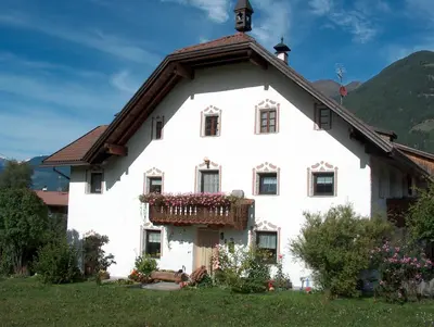 a white house with a balcony with flowers on it at Ortnerhof in Gais