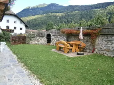 a picnic table in a yard with a stone wall at Ortnerhof in Gais