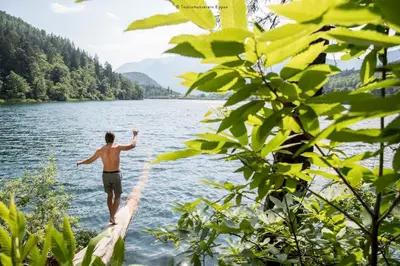 a man standing on a bridge over a lake at La Rosea - Fine Living Apartments in Appiano sulla Strada del Vino