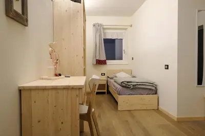 a small room with a bed and a desk and a table at B&B Le Ciorciole in Tesero