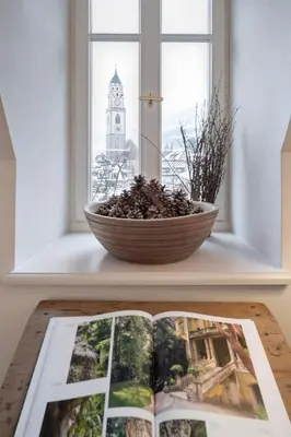 a book on a table next to a window at Steinach Townhouse Meran in Merano