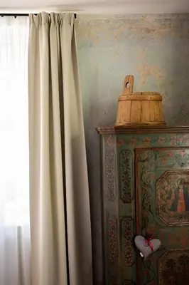 a window with a white curtain next to a cabinet at Steinach Townhouse Meran in Merano