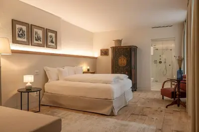 a bedroom with a large white bed and a bathroom at Steinach Townhouse Meran in Merano