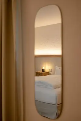 a mirror of a bedroom with a bed in a room at Steinach Townhouse Meran in Merano