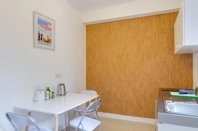 a kitchen with a white table and chairs and a wooden wall at Peters Guest House in Bolzano