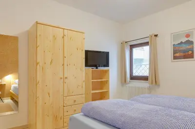 a bedroom with a bed and a wooden cabinet at Peters Guest House in Bolzano