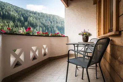 a balcony with two chairs and a table with flowers at Ciasa Scjadu in San Cassiano