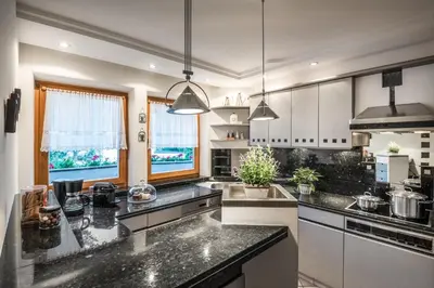 a kitchen with black granite counter tops and windows at Ciasa Scjadu in San Cassiano