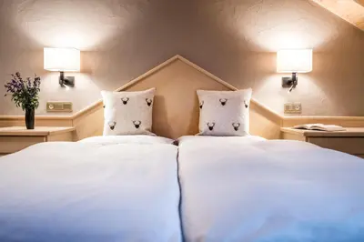 two beds in a hotel room with white sheets and pillows at Ciasa Scjadu in San Cassiano