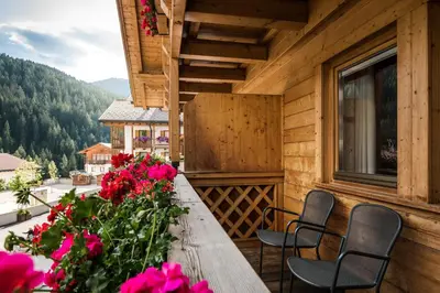 a porch with a table and chairs and flowers at Ciasa Scjadu in San Cassiano