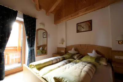 a bed in a room with a large couch at Pension Mirandola in Colfosco