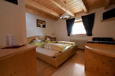 a bedroom with a bed in the corner of a room at Pension Mirandola in Colfosco