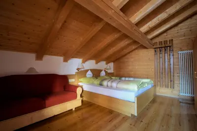 a bedroom with a bed and a couch in a room at Pension Mirandola in Colfosco