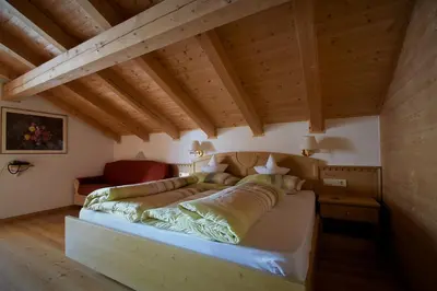 a bedroom with a large bed in a room with wooden ceilings at Pension Mirandola in Colfosco