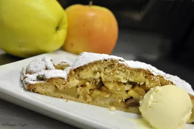 a piece of apple cake on a plate with an ice cream at Pension Mirandola in Colfosco