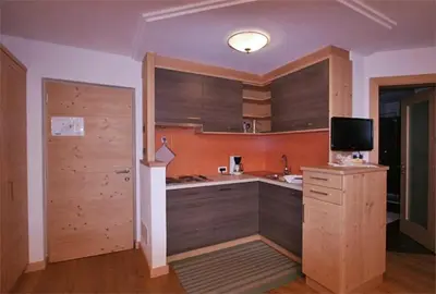 a kitchen with wooden cabinets and a tv in it at Residence Garni Stella in San Vigilio Di Marebbe