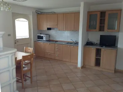 a kitchen with wooden cabinets and a table and a microwave at Appartamento Col Val di Fassa con giardino BAGNI RINNOVATI 2023 in Campitello di Fassa